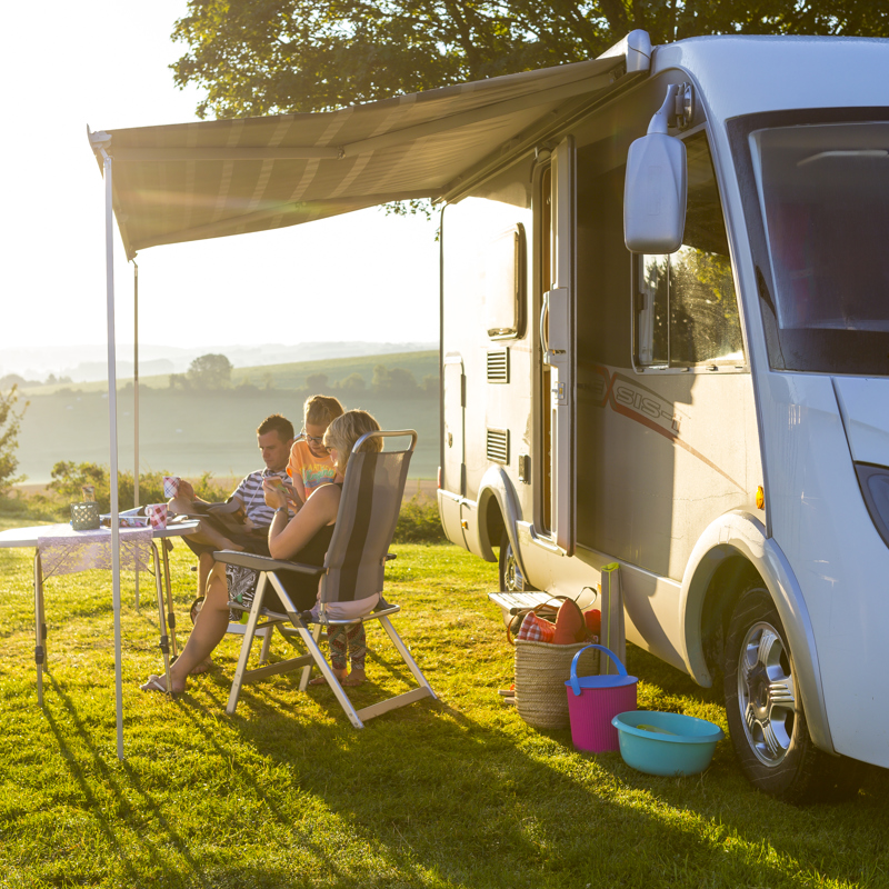 Gezin zit voor de camper op het terras met mooi uitzicht over zuid-limburg 