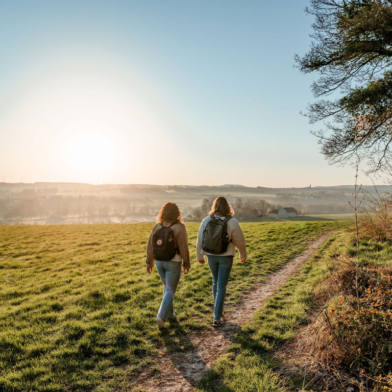 Twee wandelaars wandelen over een wandelpad bij zonsopkomst rondom de Gulperberg