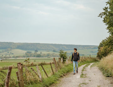 Een jonge man wandelt door een typisch Zuid-Limburgs landschap 